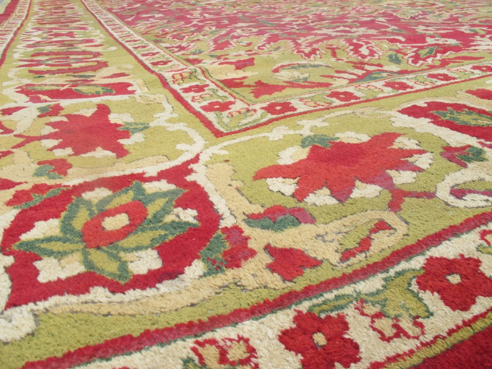 A large hand-knotted wool Amritsar carpet featuring a crimson red field decorated with olive green, cream, and pink floral vine arabesques. View VII