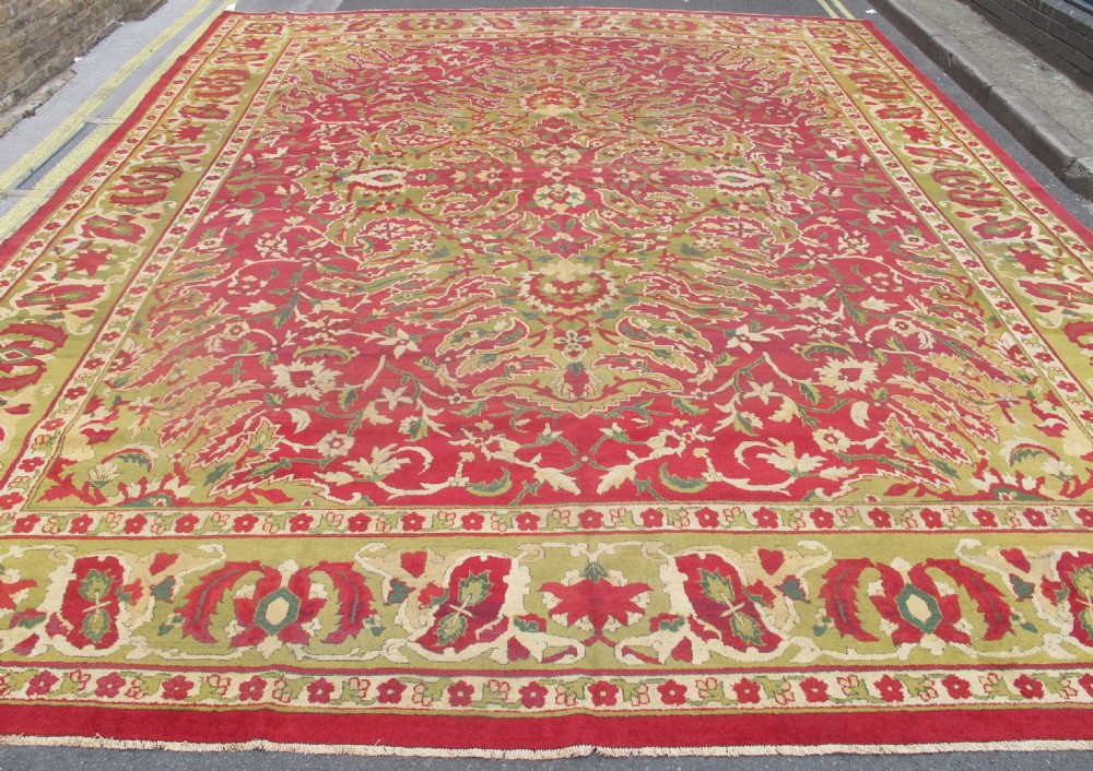 A large hand-knotted wool Amritsar carpet featuring a crimson red field decorated with olive green, cream, and pink floral vine arabesques. View VIII