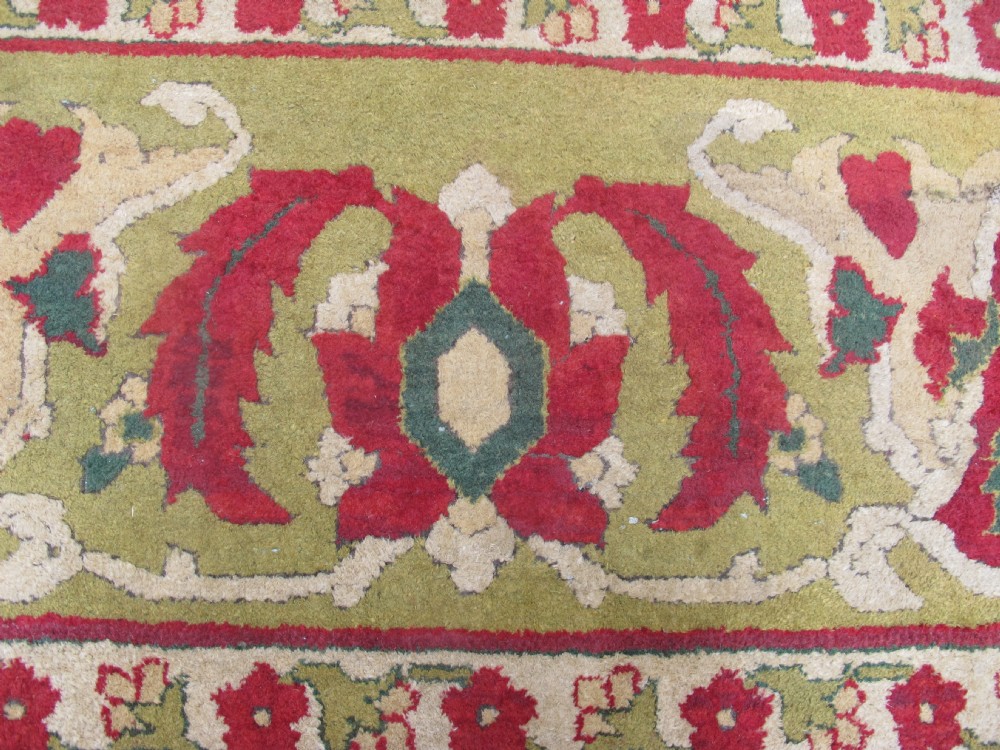 A large hand-knotted wool Amritsar carpet featuring a crimson red field decorated with olive green, cream, and pink floral vine arabesques. View IX