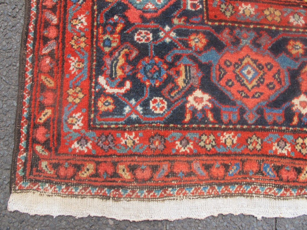 A large late 19th-century Persian Fereghan carpet featuring an unadorned terracotta red open field within a dark navy and polychrome floral border. View IV