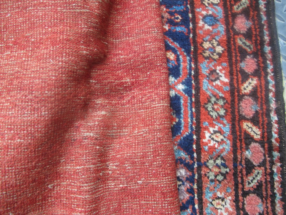 A large late 19th-century Persian Fereghan carpet featuring an unadorned terracotta red open field within a dark navy and polychrome floral border. View XI