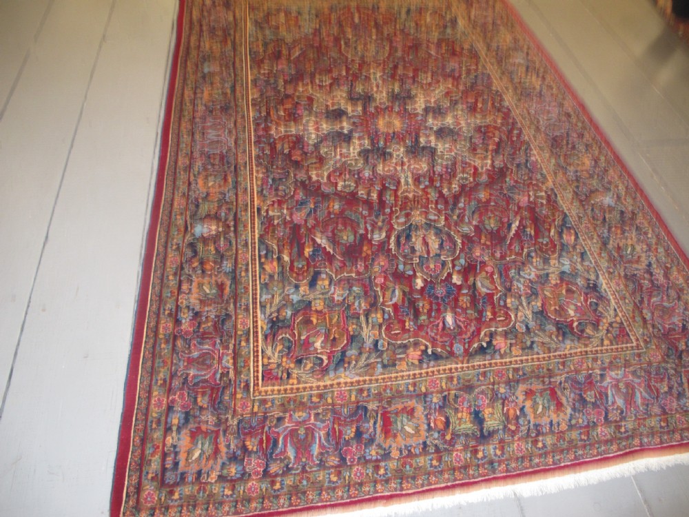 An antique Persian Meshed wool rug featuring an intricate central medallion surrounded by dense floral motifs in crimson red, navy blue, and cream. View XII
