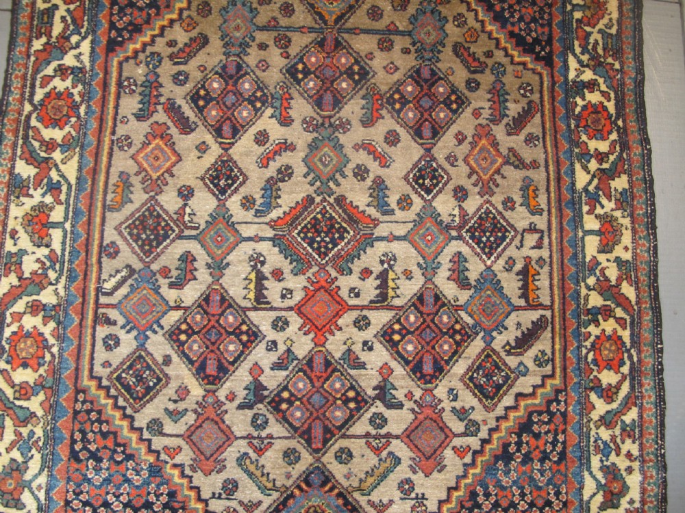 A hand-knotted antique Persian village wool rug featuring a central cream diamond medallion surrounded by geometric motifs and a navy blue field with detailed floral borders. View II