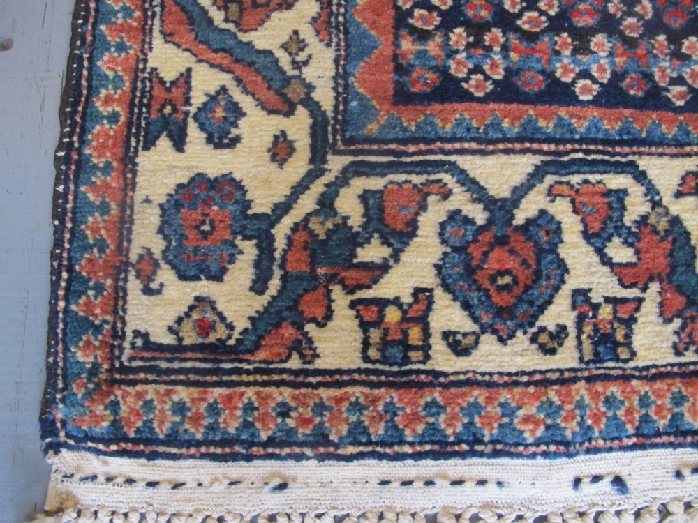 A hand-knotted antique Persian village wool rug featuring a central cream diamond medallion surrounded by geometric motifs and a navy blue field with detailed floral borders. View III