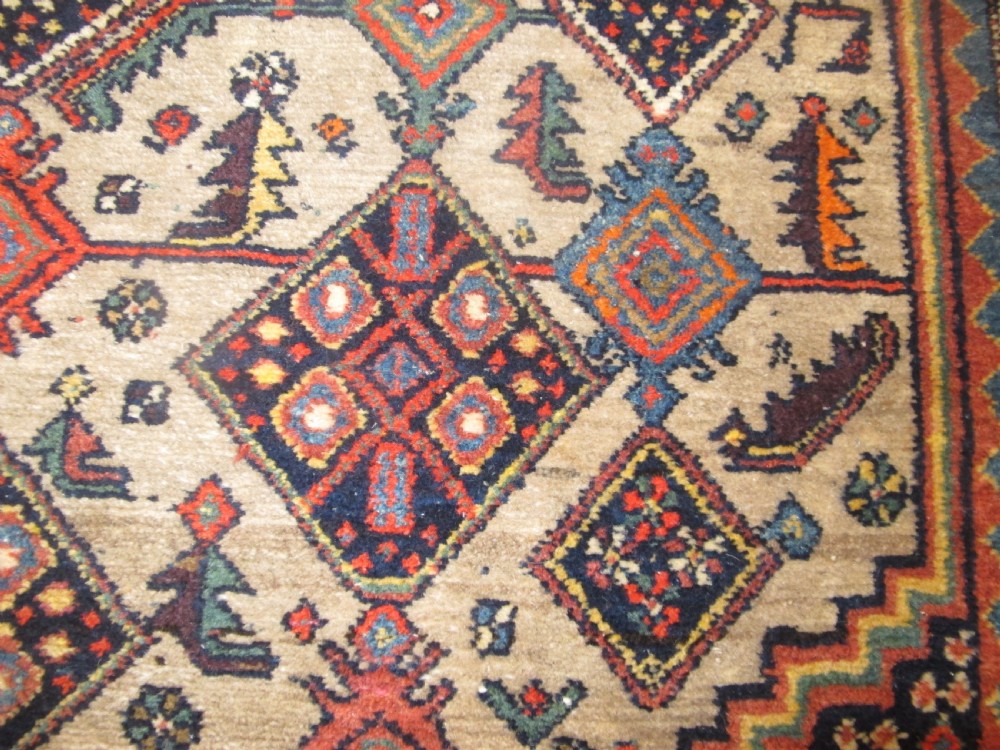A hand-knotted antique Persian village wool rug featuring a central cream diamond medallion surrounded by geometric motifs and a navy blue field with detailed floral borders. View VI