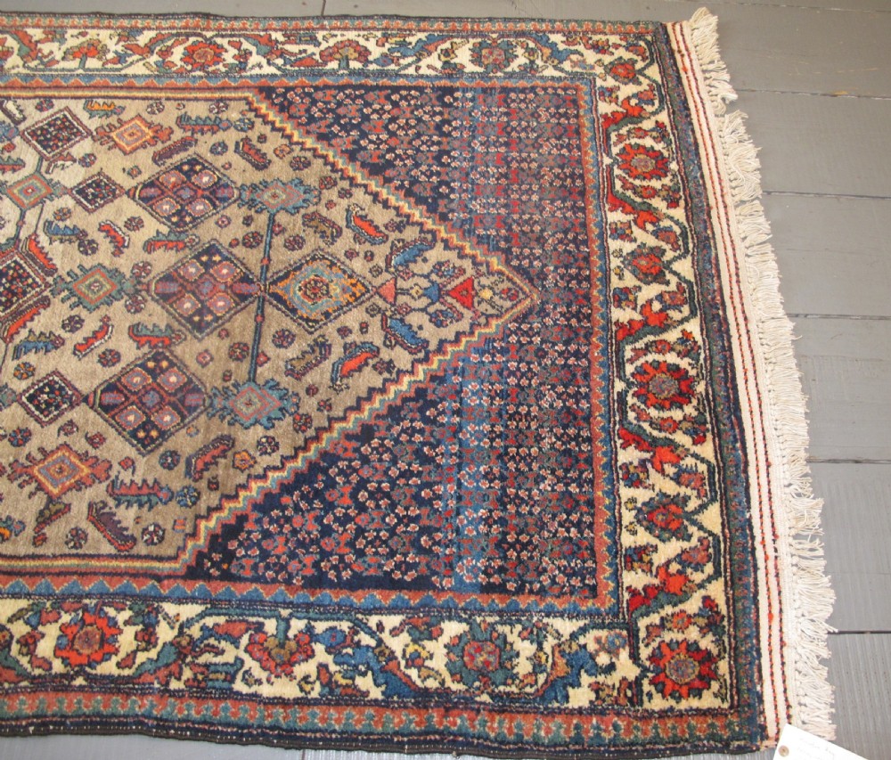 A hand-knotted antique Persian village wool rug featuring a central cream diamond medallion surrounded by geometric motifs and a navy blue field with detailed floral borders. View VIII