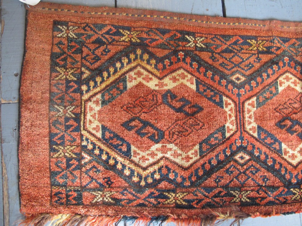 A rectangular handwoven Turkmen wool bagface displaying three repeating geometric diamond medallions in red, navy, and cream with fringed bottom edges. View II