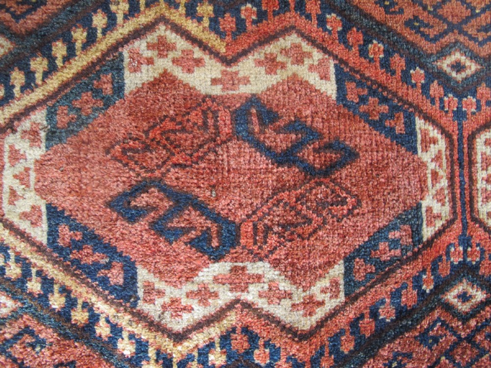 A rectangular handwoven Turkmen wool bagface displaying three repeating geometric diamond medallions in red, navy, and cream with fringed bottom edges. View III