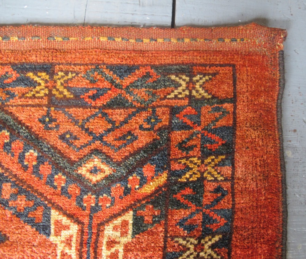 A rectangular handwoven Turkmen wool bagface displaying three repeating geometric diamond medallions in red, navy, and cream with fringed bottom edges. View VI