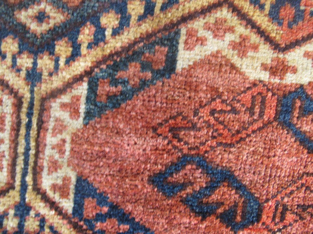 A rectangular handwoven Turkmen wool bagface displaying three repeating geometric diamond medallions in red, navy, and cream with fringed bottom edges. View VII