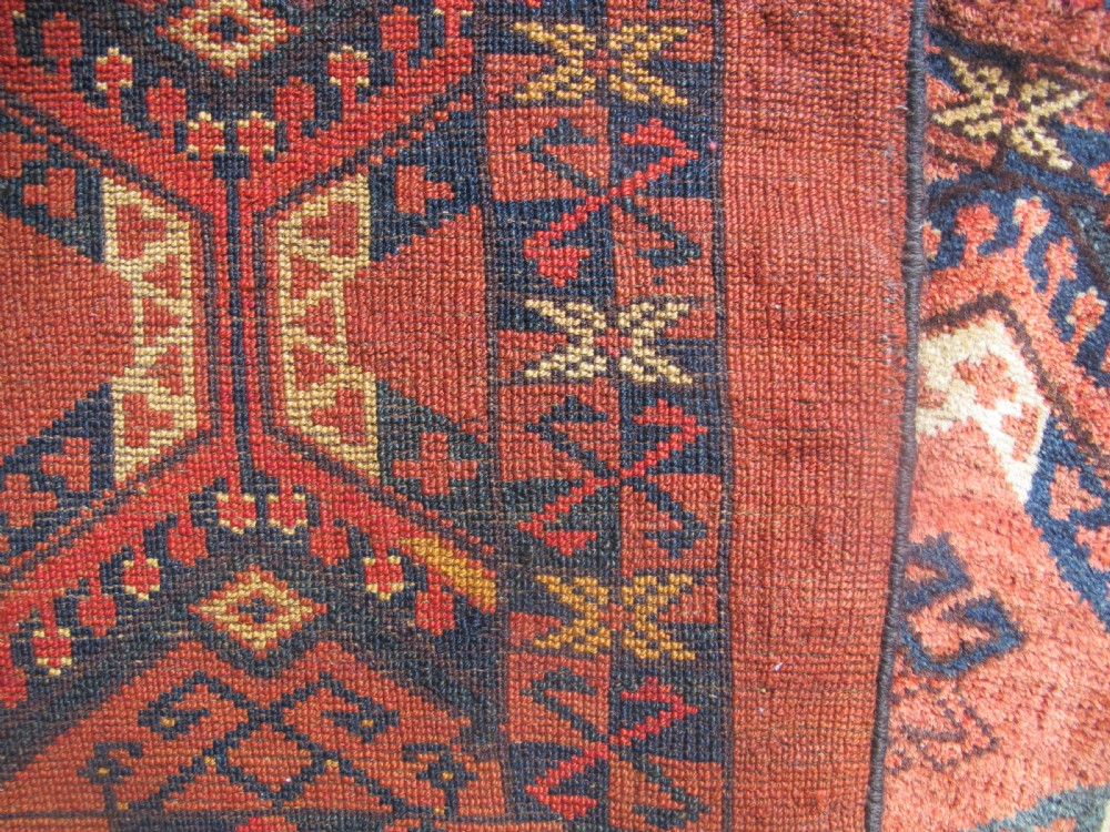 A rectangular handwoven Turkmen wool bagface displaying three repeating geometric diamond medallions in red, navy, and cream with fringed bottom edges. View VIII