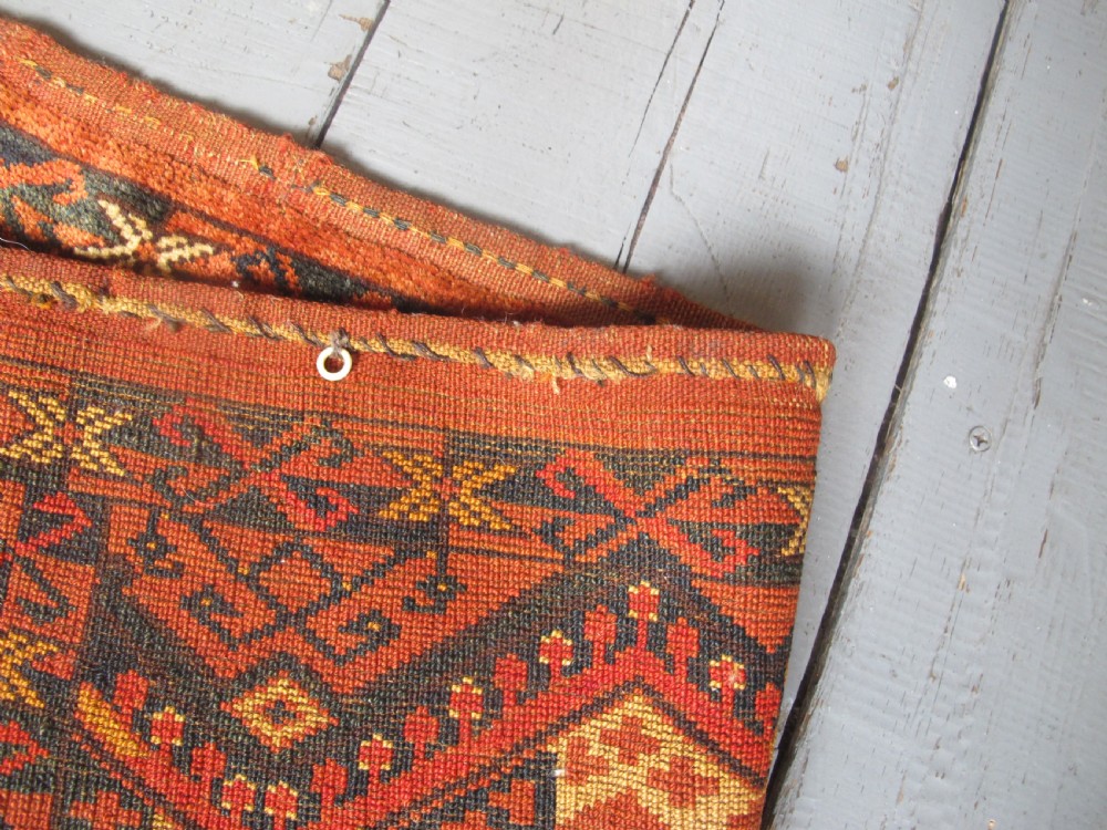 A rectangular handwoven Turkmen wool bagface displaying three repeating geometric diamond medallions in red, navy, and cream with fringed bottom edges. View IX