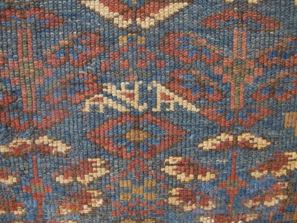 An antique hand-knotted West Persian Kurdish wool runner rug featuring repeating geometric motifs on a dark blue field framed by a patterned ochre border. View VII