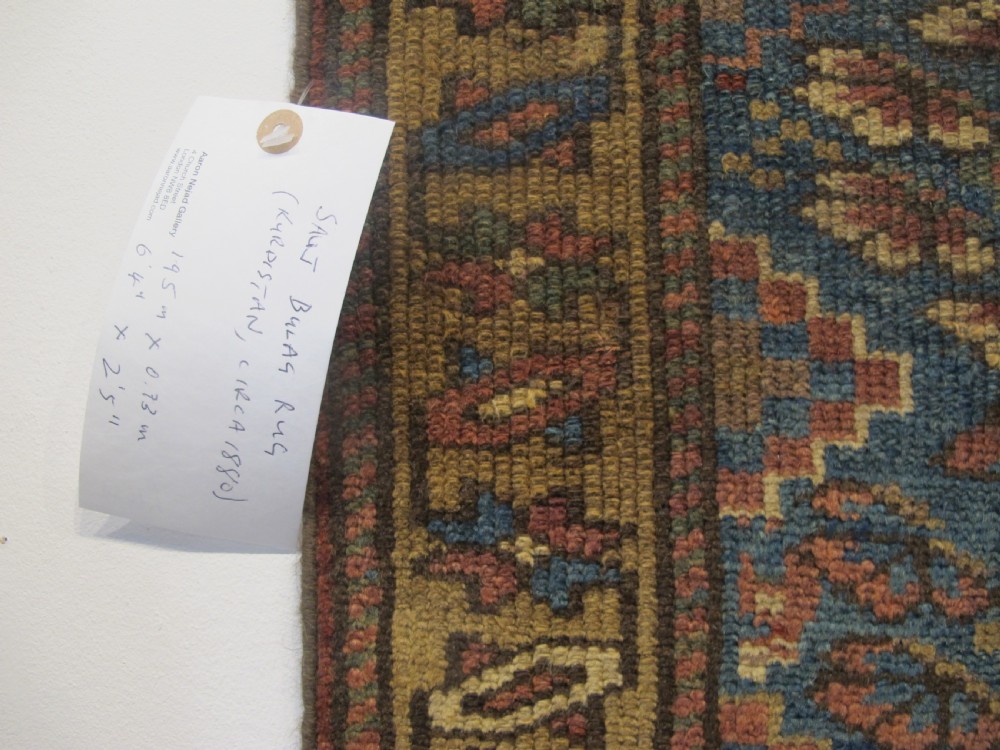 An antique hand-knotted West Persian Kurdish wool runner rug featuring repeating geometric motifs on a dark blue field framed by a patterned ochre border. View IX