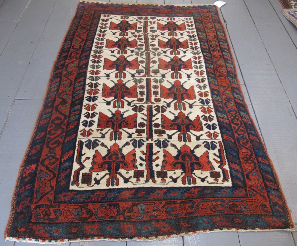 A late 19th-century Kolyai hand-knotted wool rug featuring a cream central field with stylised red and navy bird motifs framed by a geometric red border.
