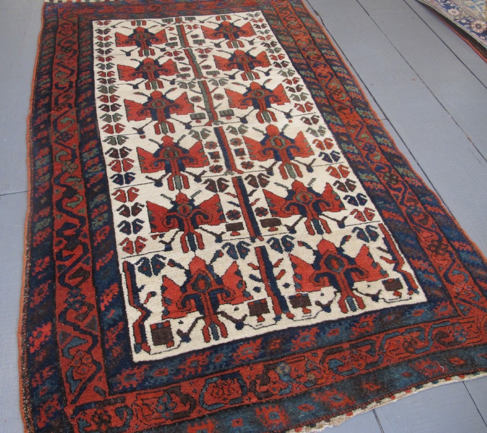 A late 19th-century Kolyai hand-knotted wool rug featuring a cream central field with stylised red and navy bird motifs framed by a geometric red border. View III