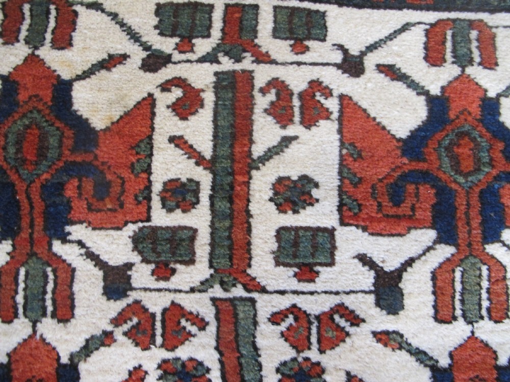 A late 19th-century Kolyai hand-knotted wool rug featuring a cream central field with stylised red and navy bird motifs framed by a geometric red border. View VII