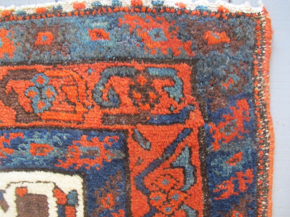 A late 19th-century Kolyai hand-knotted wool rug featuring a cream central field with stylised red and navy bird motifs framed by a geometric red border. View IX