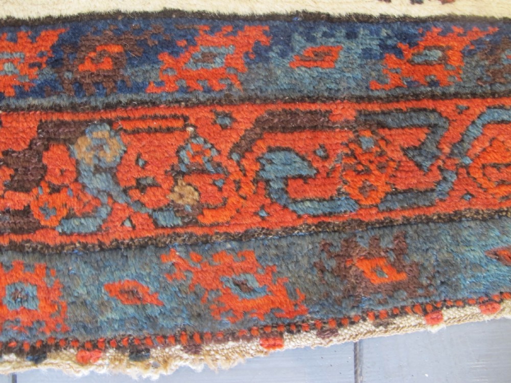 A late 19th-century Kolyai hand-knotted wool rug featuring a cream central field with stylised red and navy bird motifs framed by a geometric red border. View X