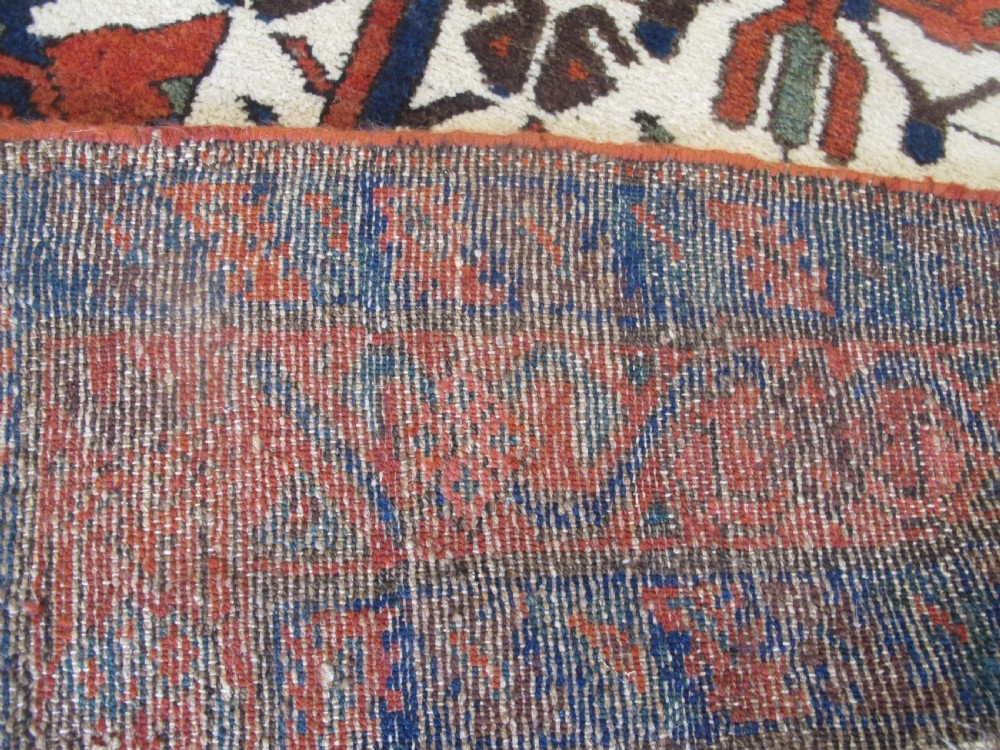 A late 19th-century Kolyai hand-knotted wool rug featuring a cream central field with stylised red and navy bird motifs framed by a geometric red border. View XI