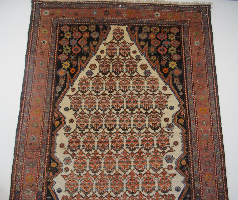 An antique hand-knotted Persian Melayir wool rug featuring an ivory central field with repeating geometric floral motifs, dark spandrels, and a terracotta border. View VII