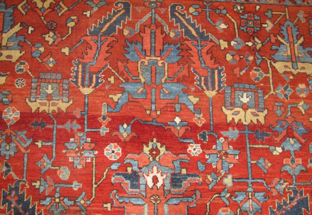 A large antique hand-knotted Persian Karaja wool carpet featuring a dominant red field with complex geometric floral medallions and a wide navy blue border. View XI