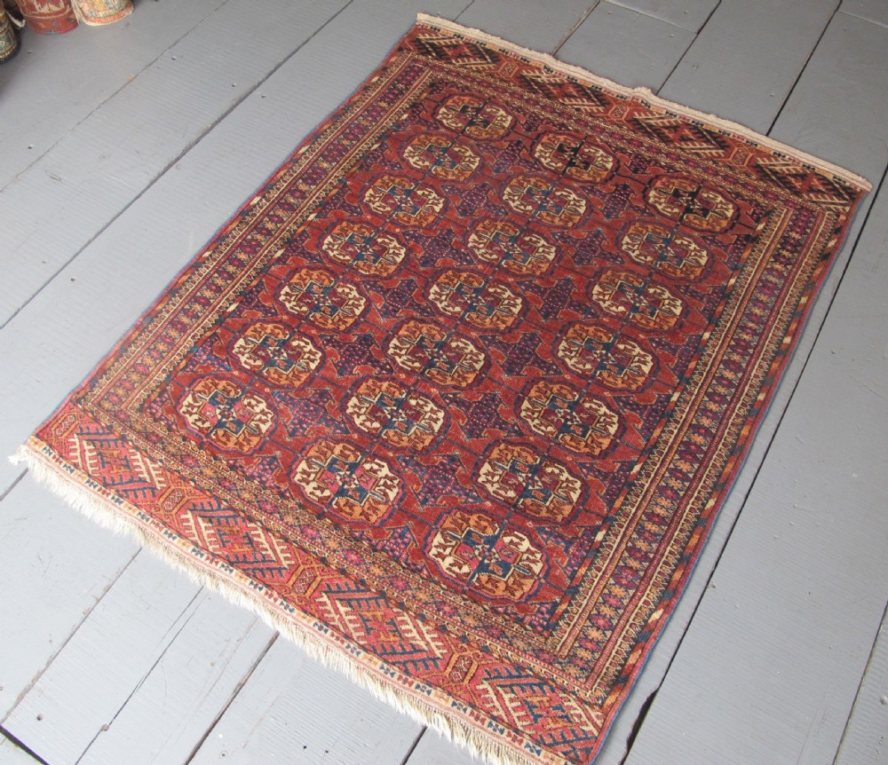 An antique woven Tekke rug featuring a deep red ground filled with grid-arranged octagonal gul motifs and geometric borders. View III