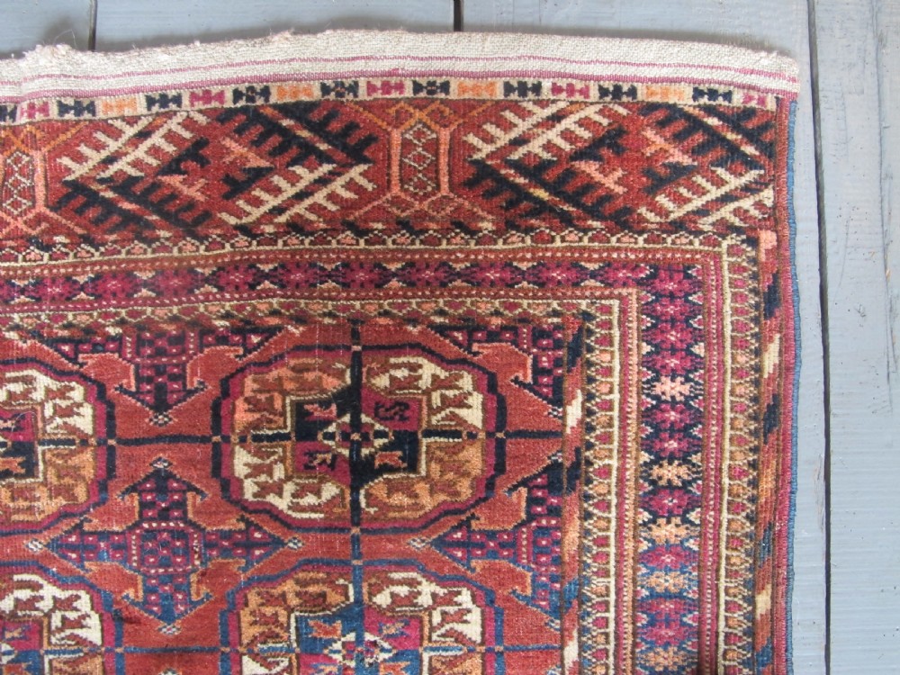 An antique woven Tekke rug featuring a deep red ground filled with grid-arranged octagonal gul motifs and geometric borders. View V