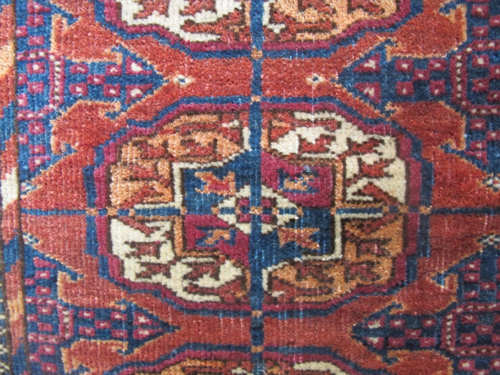 An antique woven Tekke rug featuring a deep red ground filled with grid-arranged octagonal gul motifs and geometric borders. View VI