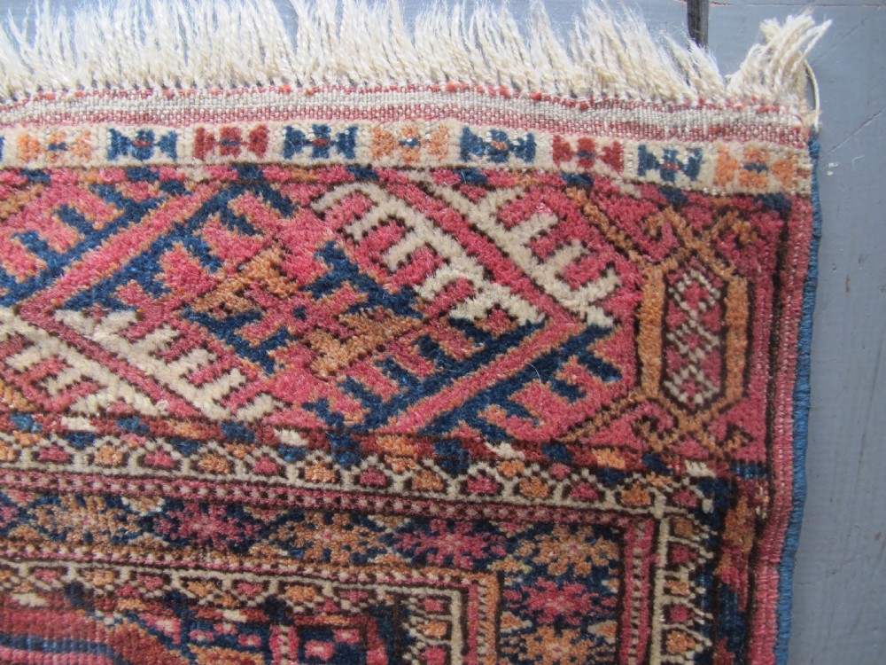 An antique woven Tekke rug featuring a deep red ground filled with grid-arranged octagonal gul motifs and geometric borders. View VII