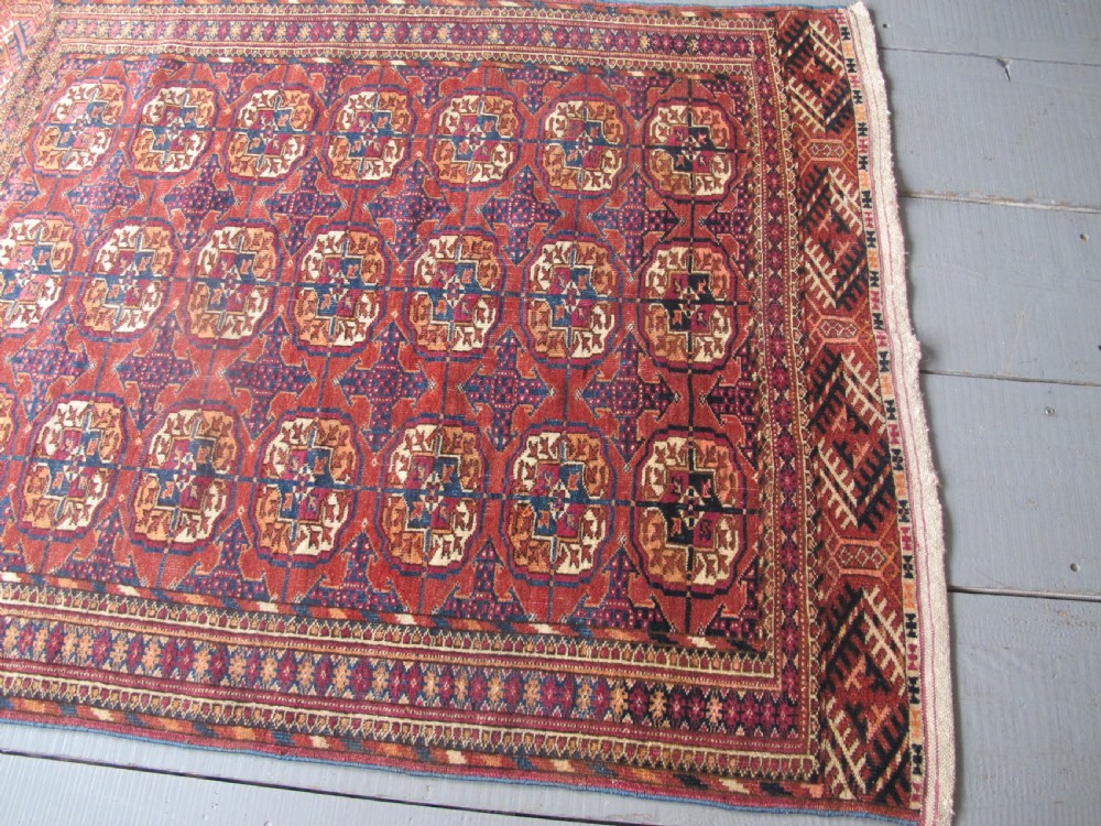 An antique woven Tekke rug featuring a deep red ground filled with grid-arranged octagonal gul motifs and geometric borders. View VIII