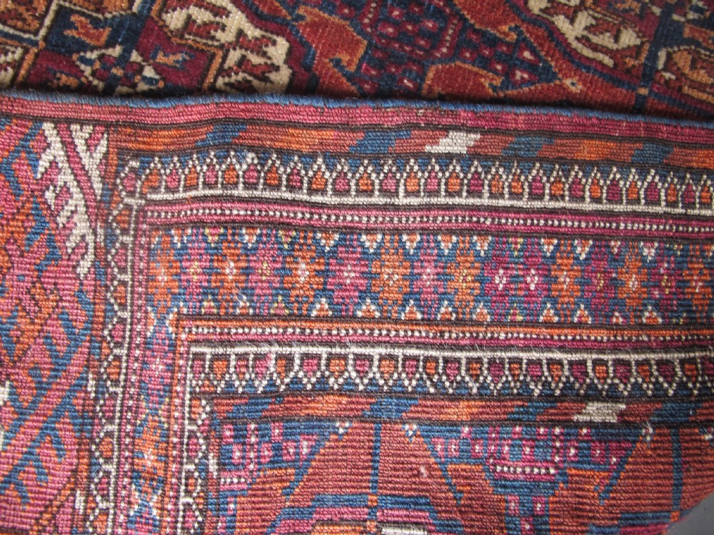 An antique woven Tekke rug featuring a deep red ground filled with grid-arranged octagonal gul motifs and geometric borders. View IX