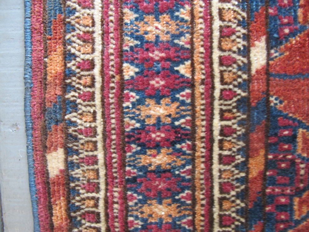 An antique woven Tekke rug featuring a deep red ground filled with grid-arranged octagonal gul motifs and geometric borders. View X