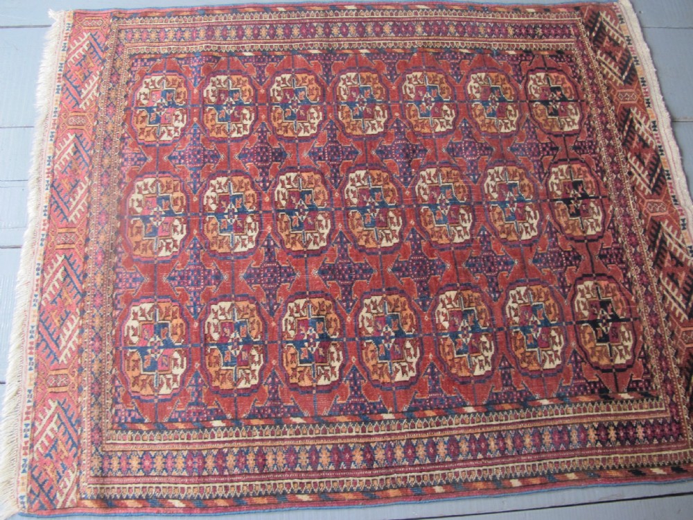 An antique woven Tekke rug featuring a deep red ground filled with grid-arranged octagonal gul motifs and geometric borders. View XI