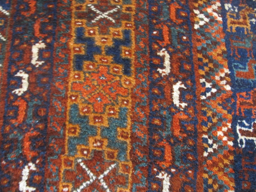 An antique hand-knotted Persian tribal rug featuring three central diamond medallions surrounded by geometric patterns in deep red, navy blue, and terracotta tones. View V