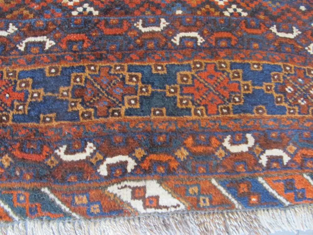 An antique hand-knotted Persian tribal rug featuring three central diamond medallions surrounded by geometric patterns in deep red, navy blue, and terracotta tones. View VI