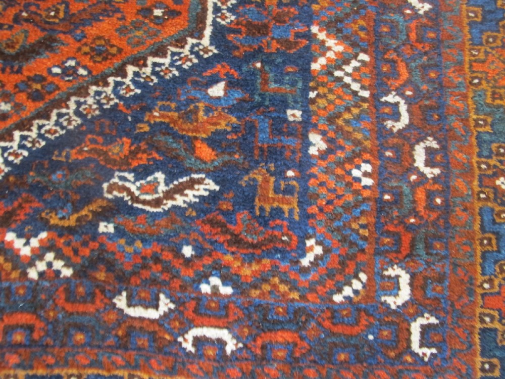 An antique hand-knotted Persian tribal rug featuring three central diamond medallions surrounded by geometric patterns in deep red, navy blue, and terracotta tones. View VIII
