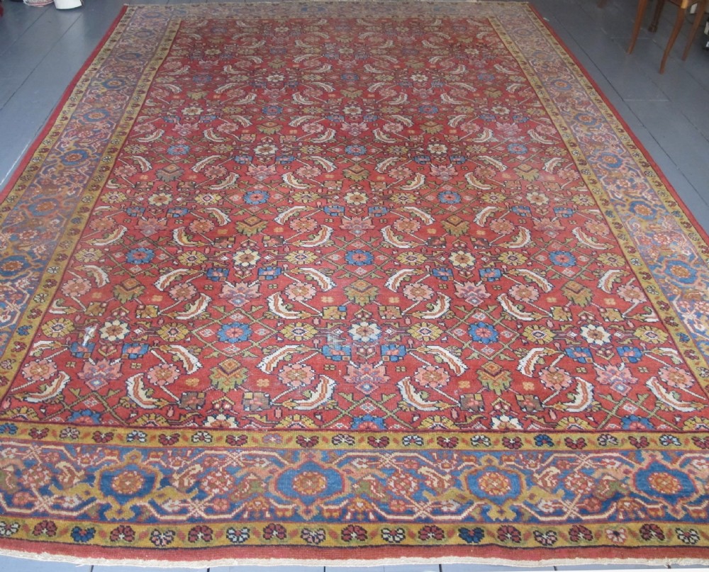 A large 19th-century antique Persian Mahal carpet featuring a terracotta red field with repeating floral lattice motifs and broad multi-tiered decorative borders.