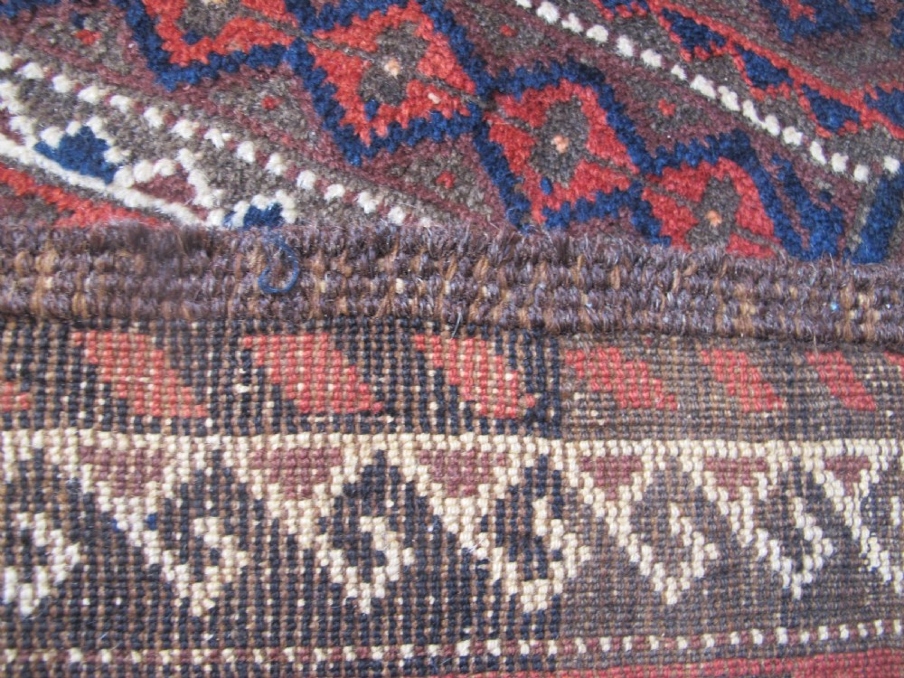 An antique hand-woven Belouch wool rug featuring geometric octagonal medallions in deep red, navy blue, and dark brown tones. View XIII