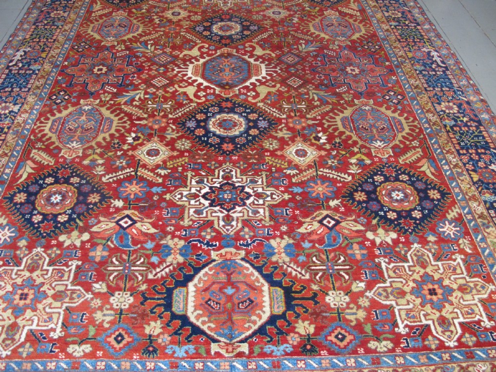 An antique late 19th-century Persian Karaja wool carpet featuring a terracotta red field filled with geometric medallions and surrounded by a detailed dark indigo border. View III