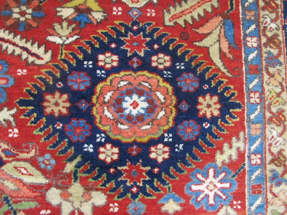 An antique late 19th-century Persian Karaja wool carpet featuring a terracotta red field filled with geometric medallions and surrounded by a detailed dark indigo border. View IX