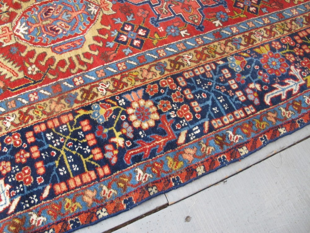 An antique late 19th-century Persian Karaja wool carpet featuring a terracotta red field filled with geometric medallions and surrounded by a detailed dark indigo border. View XI