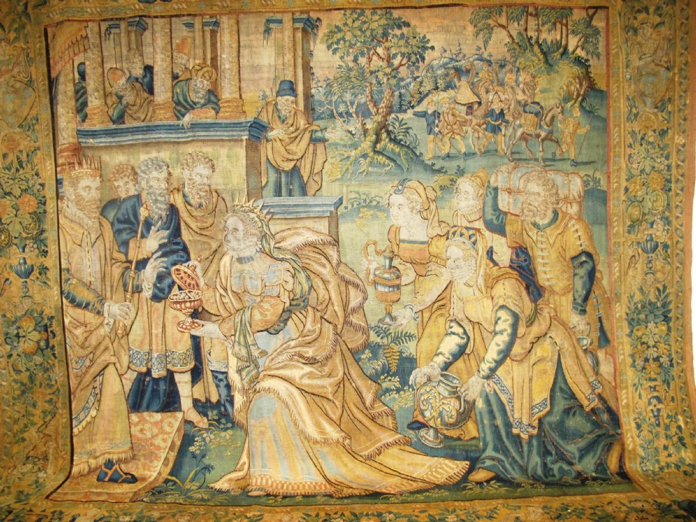 A large 16th-century Flemish Renaissance tapestry woven with figures in classical attire framed by an elaborate floral and fruit border. View II