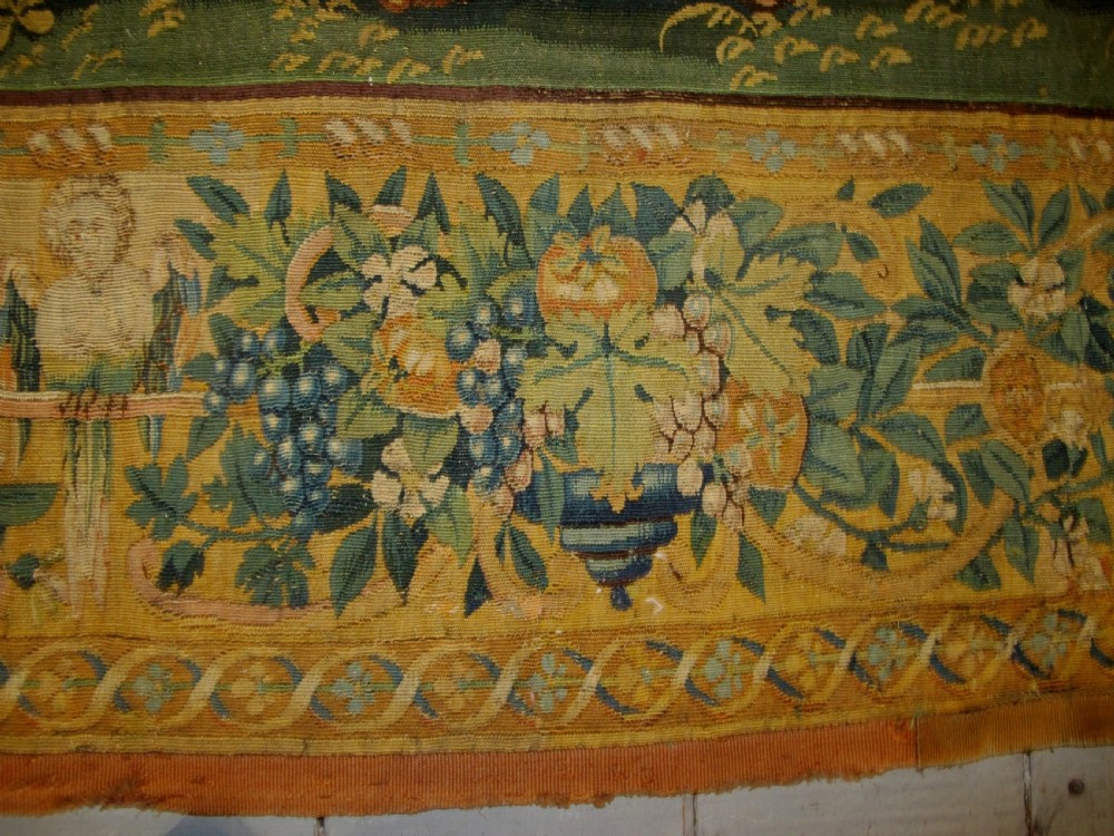 A large 16th-century Flemish Renaissance tapestry woven with figures in classical attire framed by an elaborate floral and fruit border. View XI