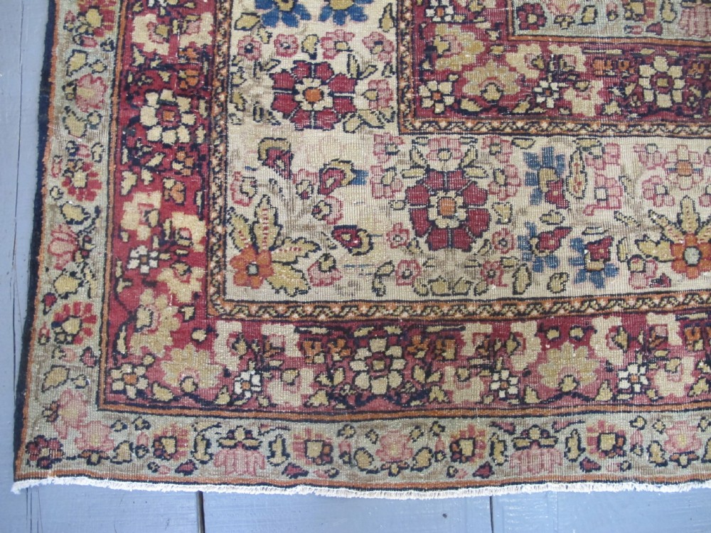 A large 19th-century Kirman Laver hand-knotted wool carpet featuring a central starburst floral medallion on an ivory ground surrounded by multi-banded floral borders in shades of crimson and navy blue. View IV
