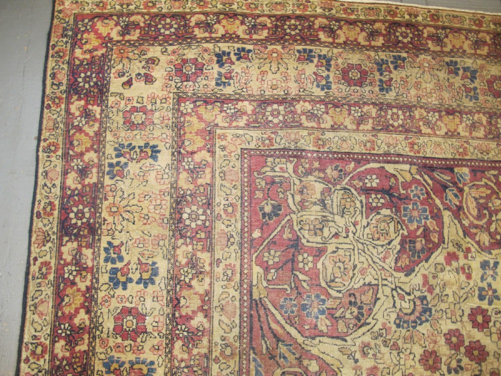 A large 19th-century Kirman Laver hand-knotted wool carpet featuring a central starburst floral medallion on an ivory ground surrounded by multi-banded floral borders in shades of crimson and navy blue. View VIII