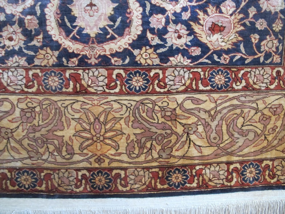A mid-20th-century Turkish silk rug featuring a dark navy mihrab arch filled with floral motifs, surrounded by an ochre border with calligraphic script and bird illustrations. View IV