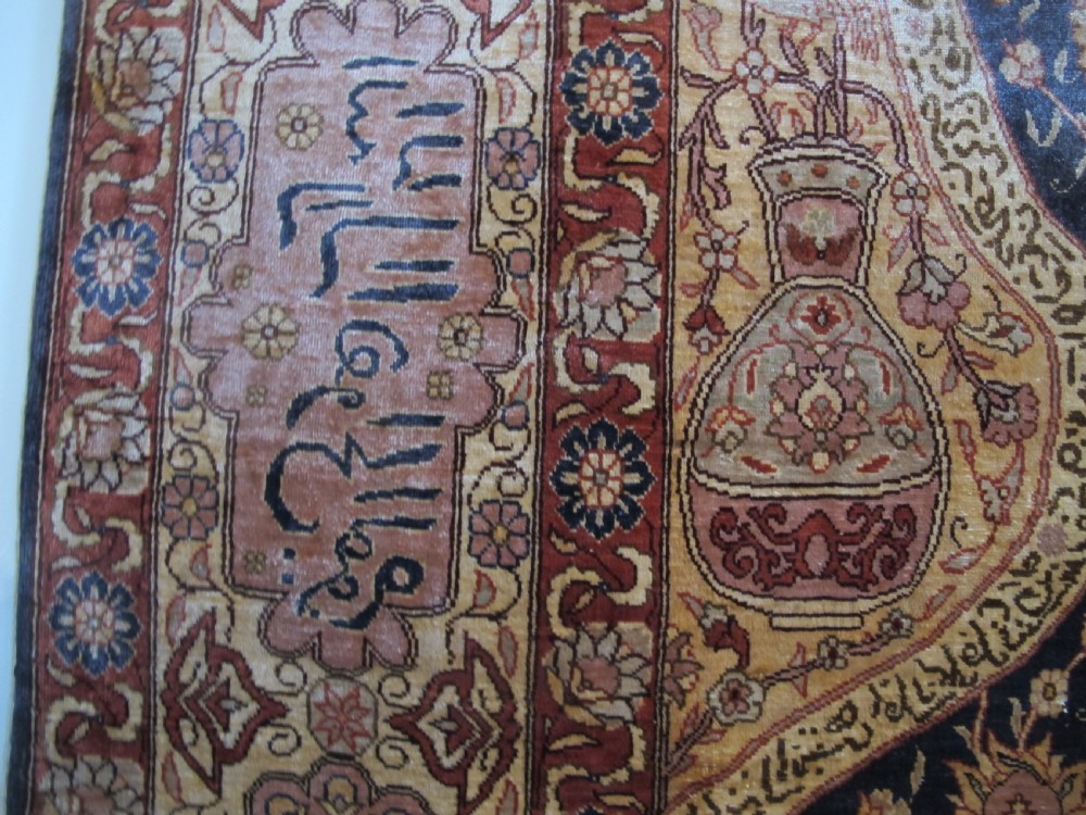 A mid-20th-century Turkish silk rug featuring a dark navy mihrab arch filled with floral motifs, surrounded by an ochre border with calligraphic script and bird illustrations. View VIII