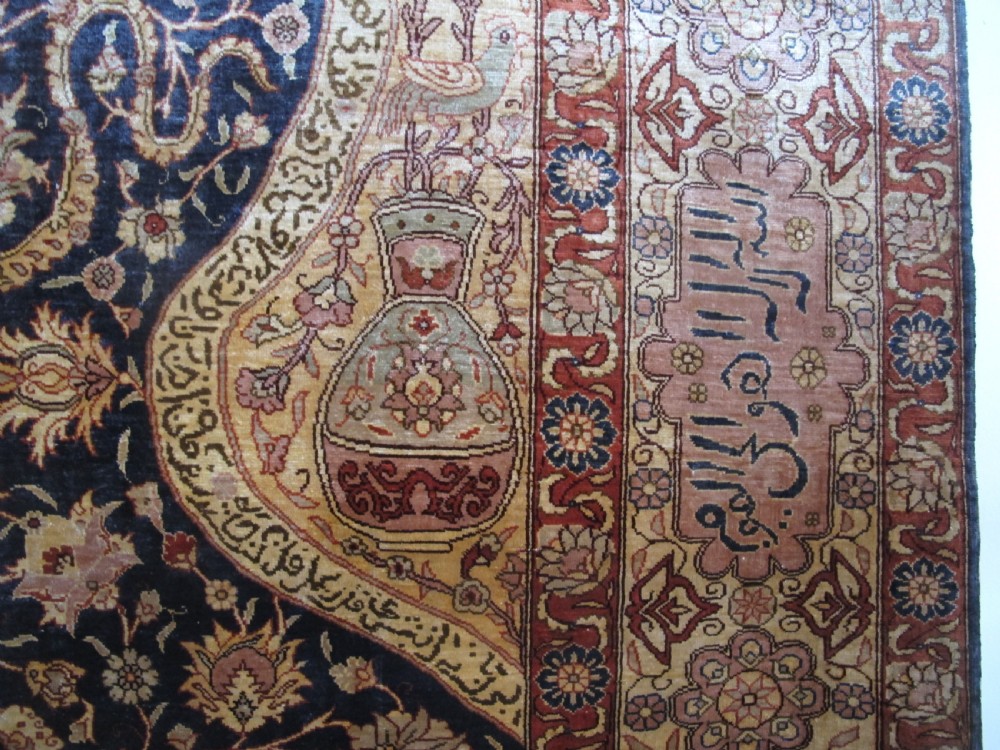 A mid-20th-century Turkish silk rug featuring a dark navy mihrab arch filled with floral motifs, surrounded by an ochre border with calligraphic script and bird illustrations. View IX