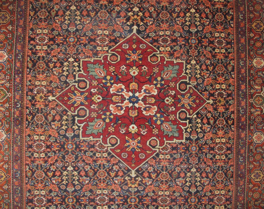An antique hand-knotted Persian Fereghan wool rug featuring a central terracotta diamond medallion set within a dense navy blue floral field and ornate multi-layered borders. View II